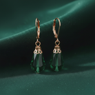 Green teardrop earrings with rose gold hooks on a green background
