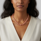 Woman wearing a pink beaded necklace against a neutral background