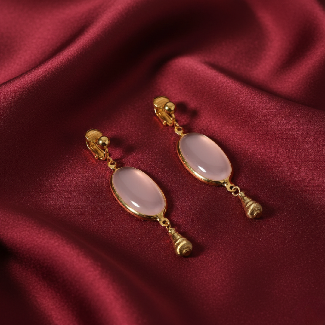 Gold earrings with pink stones on a red fabric background