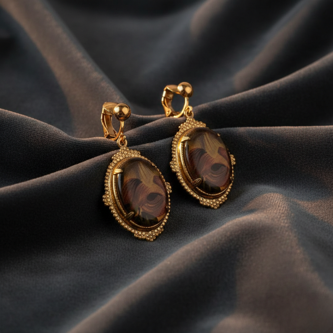 Gold earrings with brown gemstones on a dark fabric background