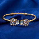 Gold tone spring bracelet with over a dozen sparkling clear crystals on blue fabric