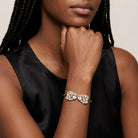 Woman in a black top wearing a gold tone spring bracelet with over a dozen sparkling clear crystals