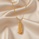Gold necklace with a pendant on a beige fabric background