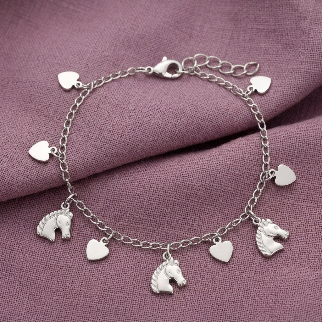 Silver tone horse and heart charms bracelet on a light purple fabric surface