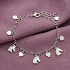 Silver tone horse and heart charms bracelet on a light purple fabric surface