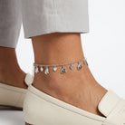 Anchored anklet with heart and horse-shaped charms on a person's ankle against a neutral background