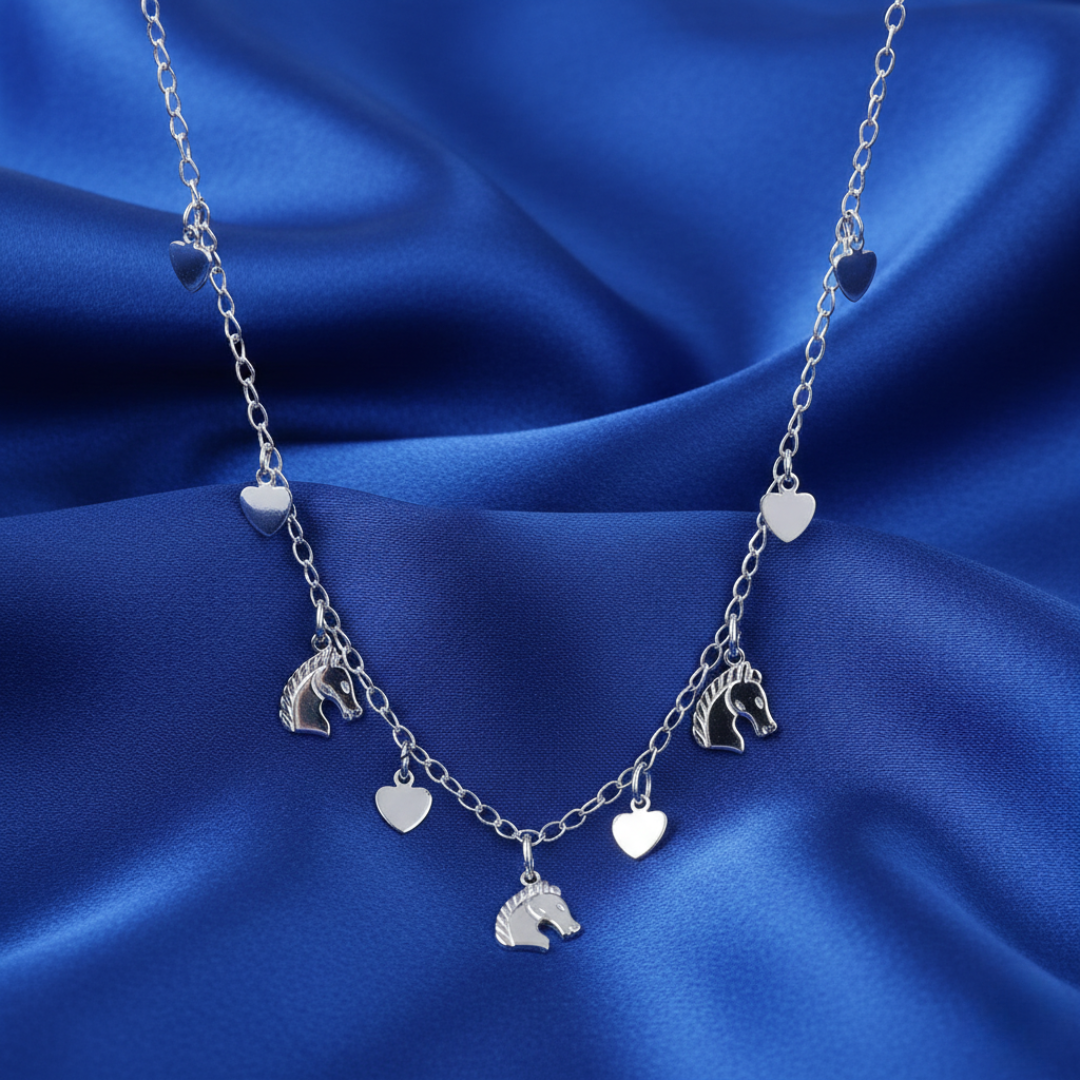 Silver necklace with heart and horsehead charms on a blue satin background