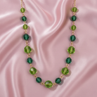 Green beaded necklace on a pink satin background