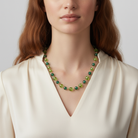 Woman wearing a green beaded necklace against a neutral background
