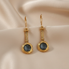 Gold earrings with blue crystals on a beige fabric background