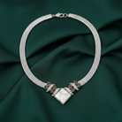 Silver necklace with decorative elements on a dark green fabric background