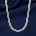 Silver tube chain necklace on a dark blue fabric background
