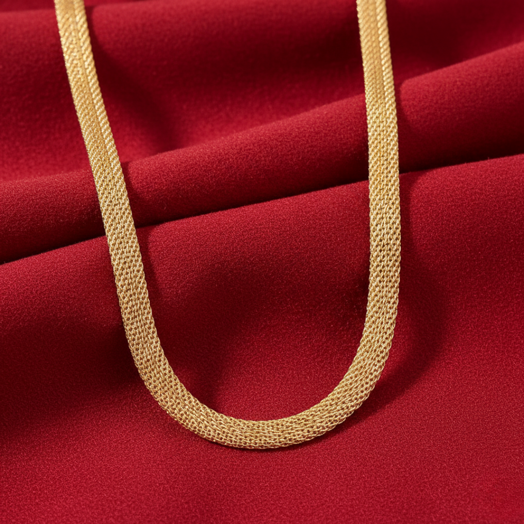 Gold tube chain necklace on a red fabric background