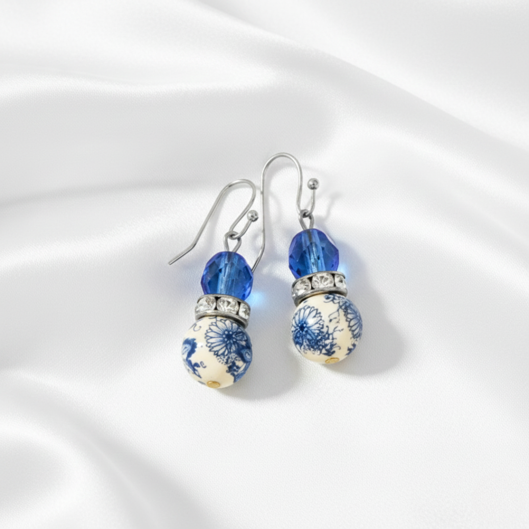 Pair of earrings with blue and white floral design on a white background