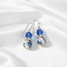 Pair of earrings with blue and white floral design on a white background