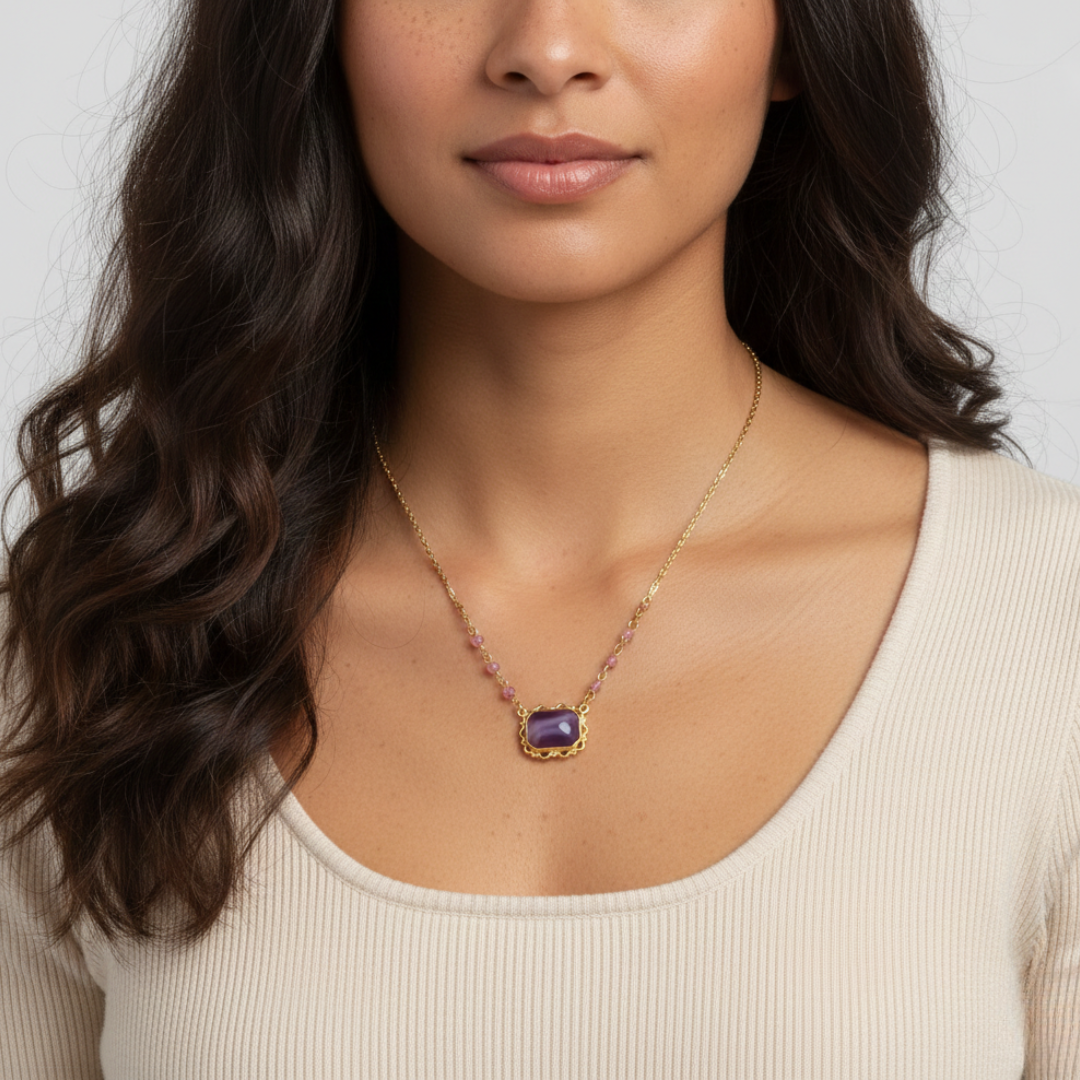 Woman wearing a gold necklace with a purple pendant against a neutral background