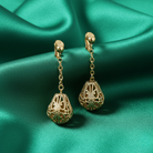 Gold earrings on a green satin background
