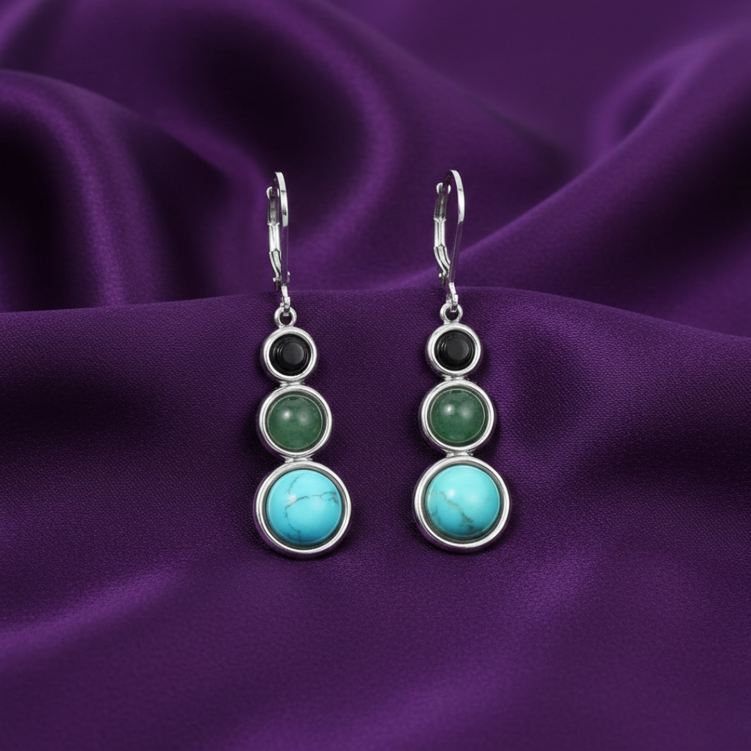 Silver earrings with green and turquoise stones on a purple fabric background