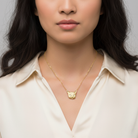Woman wearing a gold necklace with a bear pendant against a neutral background