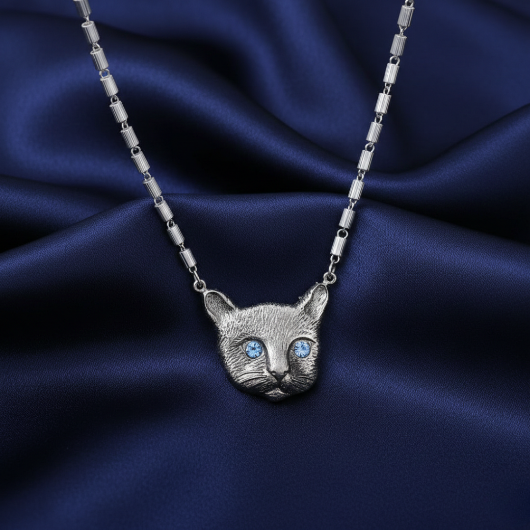 Silver cat pendant necklace on a blue satin background
