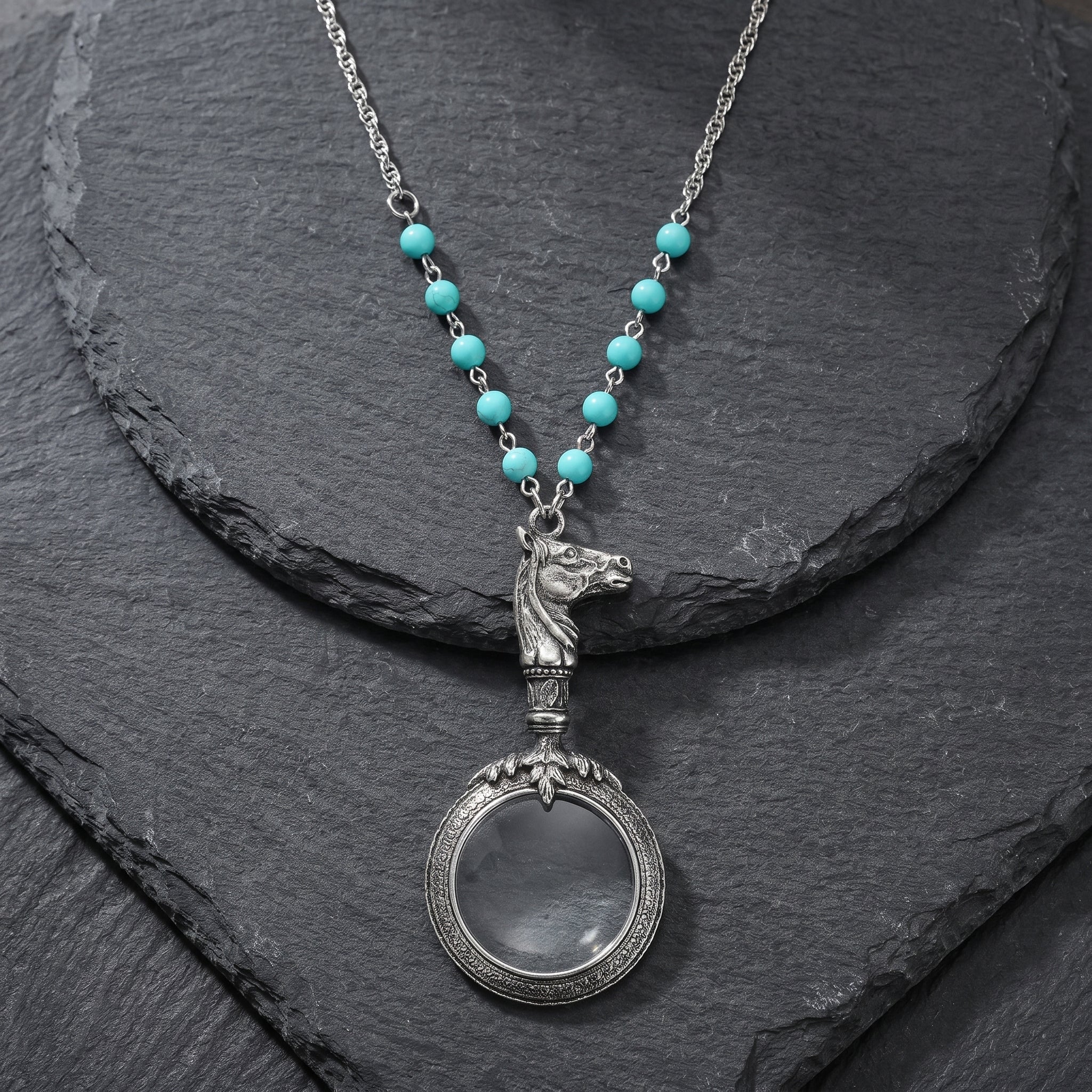 Turquoise Bead Equine Magnifying Glass Pendant Necklace resting on dark stone surface