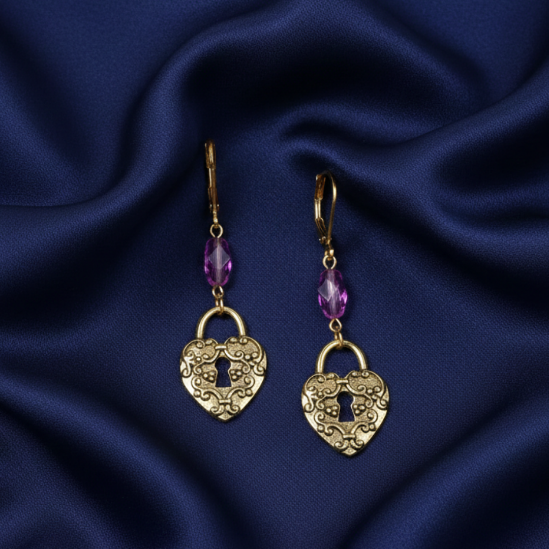 Gold heart-shaped lock earrings with purple crystals on a blue satin background