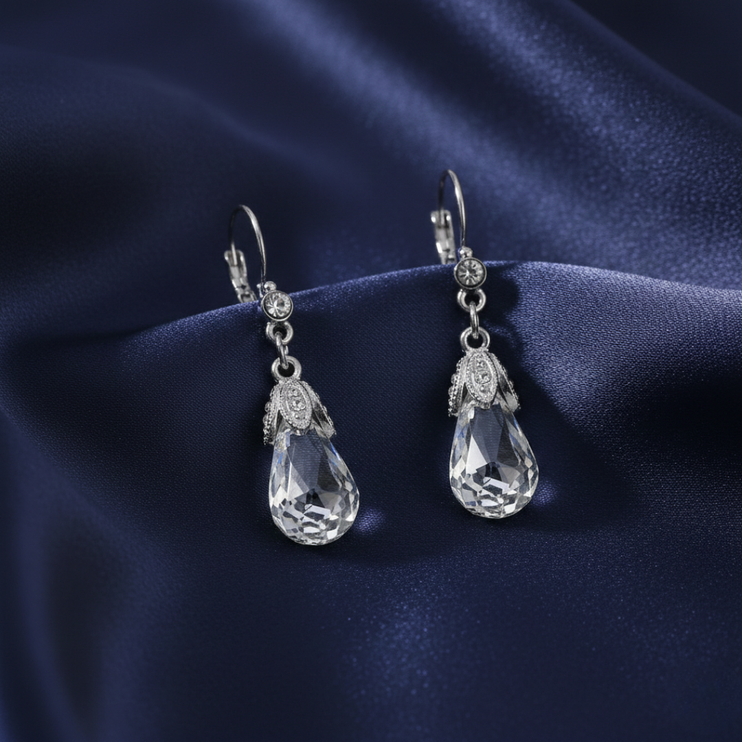 Teardrop-shaped crystal earrings on a dark blue satin background