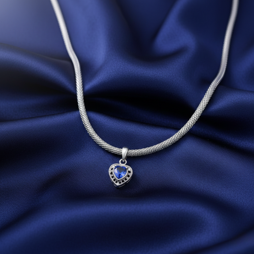 Silver necklace with a heart-shaped blue gemstone pendant on a blue fabric background