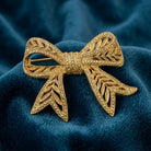 Gold bow-shaped brooch on a blue velvet background