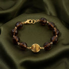 Bracelet with brown beads and gold accents on a green fabric background