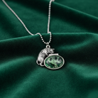 Silver necklace with a bear pendant on a green fabric background