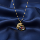 Gold necklace with a pendant featuring a cartoon character on a blue satin background