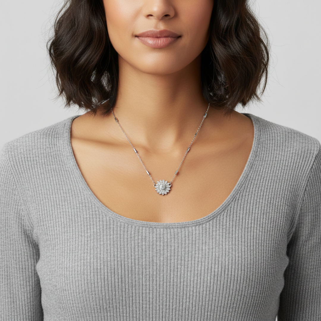 Woman wearing a silver necklace with a floral pendant full of crystals on a plain background