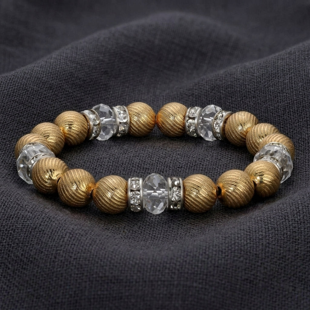Bracelet with gold tone beads and clear crystals on a dark fabric background