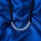 Necklace with black beads and clear crystals on a blue satin background