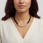 Woman wearing a black and silver beaded necklace against a neutral background