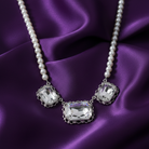 Faux pearl necklace with crystal pendants on a purple satin background
