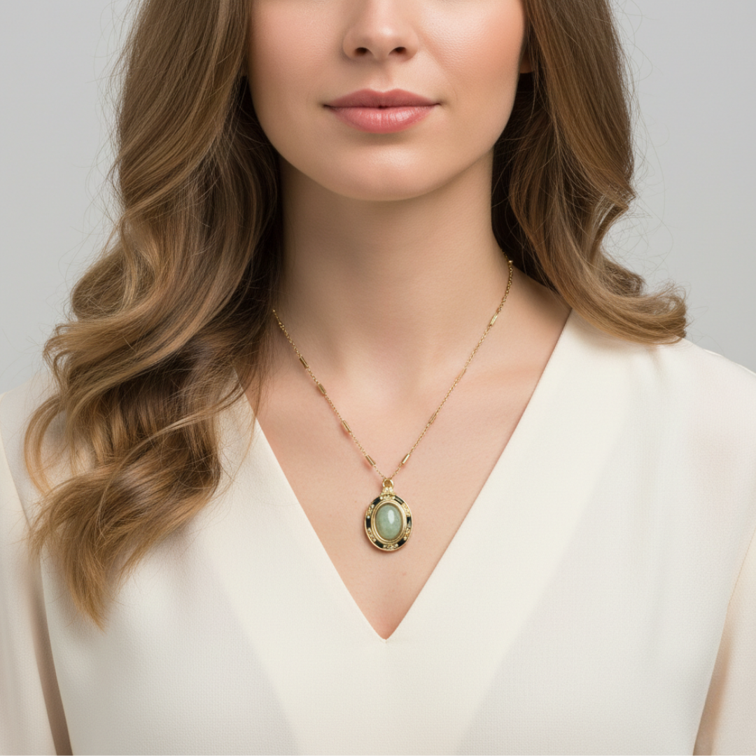 Woman wearing a gold necklace with a green pendant against a neutral background