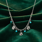 Necklace with horse charms and turquoise beads on a green fabric background