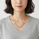Woman wearing a silver necklace with heart-shaped charms on a plain background