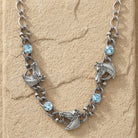 Silver necklace with horse charms and blue crystals on a beige stone background