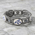 Decorative silver bracelet with blue and white patterns on a marble surface