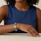 Woman wearing a blue sleeveless top and a silver and blue bracelet