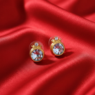 Gold earrings with blue crystals on a red satin background