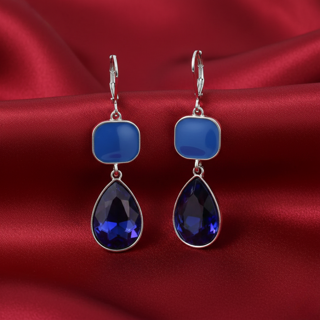 Blue teardrop earrings on a red satin background