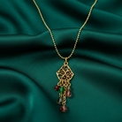 Gold necklace with a pendant and colorful beads on a green fabric background