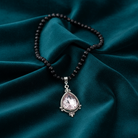 Necklace with a teardrop pendant on dark green fabric