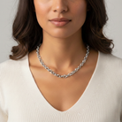 Woman wearing a silver chain necklace against a neutral background