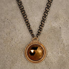 Necklace with a round topaz crystal pendant on a textured surface