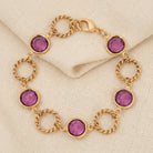Gold bracelet with purple Austrian crystals on a beige fabric background